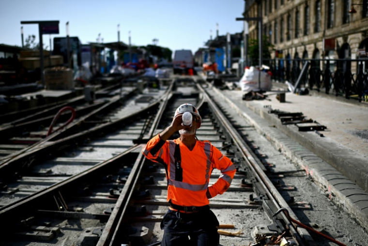 Un ouvrier se désaltère sur le chantier d'une ligne de tramway à Bordeaux, le 1er juillet 2025 ( AFP / Christophe ARCHAMBAULT )