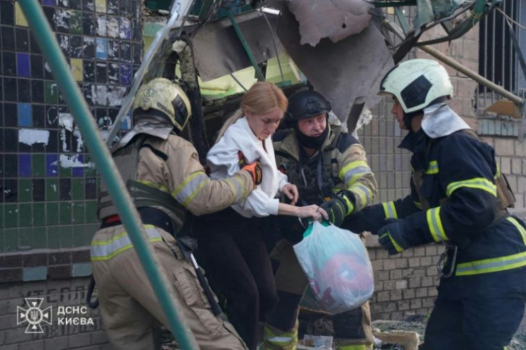 Photo diffusée et publiée par le Service d'urgence ukrainien, le 23 juin 2025, de secouristes évacuant des habitants d'un bâtiment endommagé après des frappes nocturnes de drones et de missiles russes à Kiev ( Service d'urgence ukrainien / Handout )