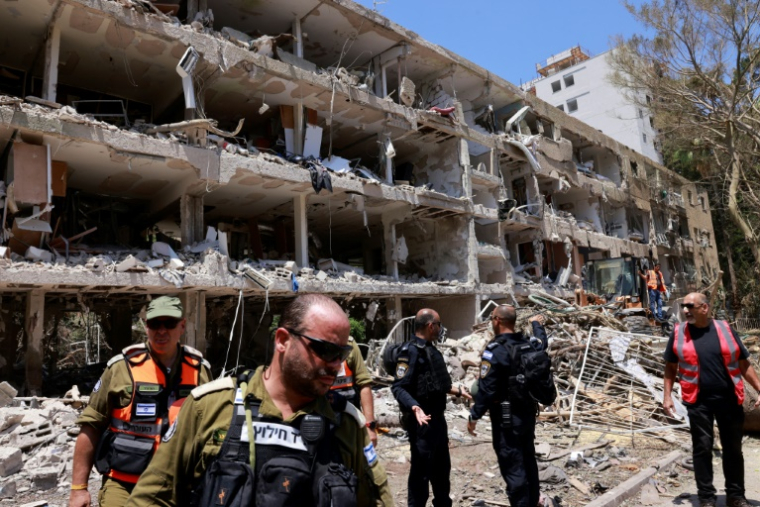 Des secouristes et des membres des forces de sécurité israéliens devant un immeuble lourdement endommagé par des frappes iraniennes à Tel-Aviv, le 22 juin 2025 ( AFP / Menahem Kahana )
