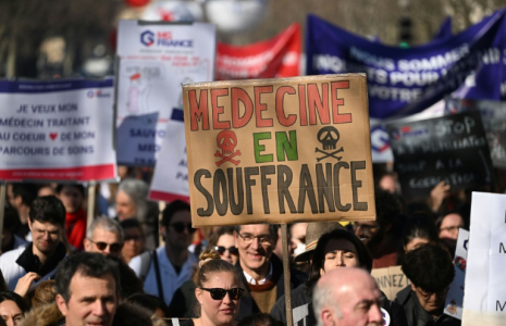 Un manifestant brandit une pancarte "Médecine en souffrance" lors d'une mobilisation du secteur privé, le 14 février 2023 à Paris ( AFP / Emmanuel DUNAND )