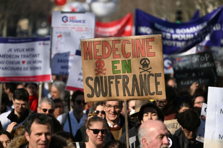 Un manifestant brandit une pancarte "Médecine en souffrance" lors d'une mobilisation du secteur privé, le 14 février 2023 à Paris ( AFP / Emmanuel DUNAND )
