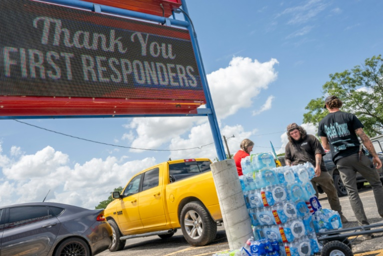 Des volontaires distribuent des bouteilles d'eau alors que les secours poursuivent leurs recherches pour retrouver des survivants après les inondations meurtrières qui ont frappé le texas, à Kerville, le 8 juillet 2025 ( GETTY IMAGES NORTH AMERICA / Brandon Bell )
