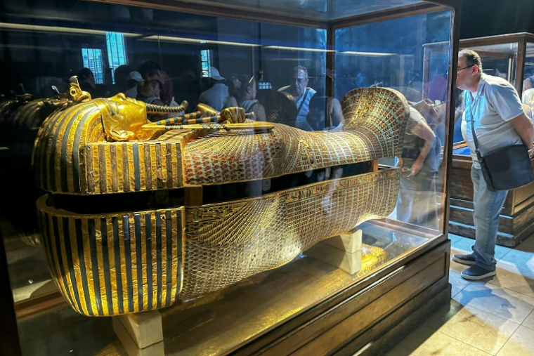 Des touristes admirent le sarcophage extérieur en bois doré de l'ancien roi égyptien Toutânkhamon au musée du Caire, le 11 juin 2025 ( AFP / Khaled DESOUKI )