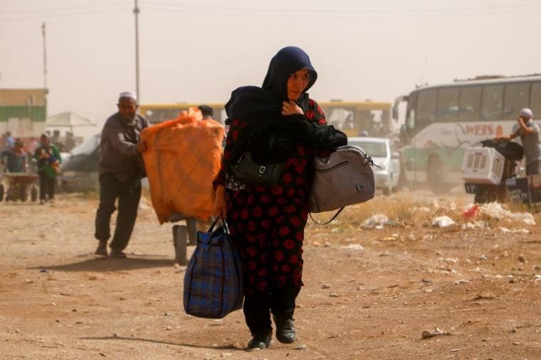 Des réfugiés afghans arrivent à la frontière entre l'Iran et l'Afghanistan, le 5 juillet 2025 ( AFP / Mohsen KARIMI )