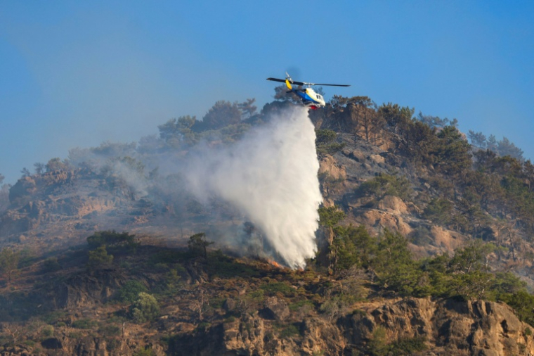 Un hélicoptère largue de l'eau sur un feu près de Ierapetra sur l'île grecque de Crète, le 3 juillet 2025 ( AFP / Costas Metaxakis )