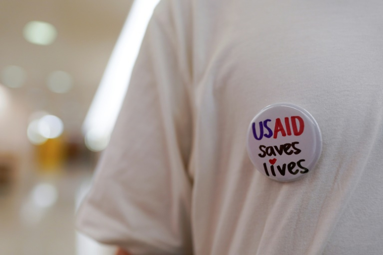 Un ancien employé fédéral porte un badge "USAID sauve des vies", lors d'un sit-in le 24 juin 2025 à Washington ( GETTY IMAGES NORTH AMERICA / Jemal Countess )