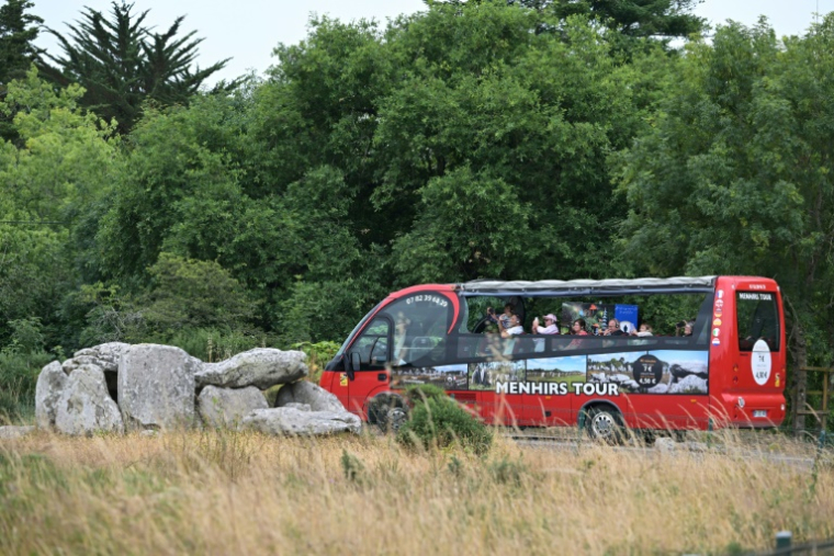 Des touristes prennent des photos des Mégalithes de Carnac, lors d'une visite en bus, le 27 juin 2025 dans le Morbihan ( AFP / Damien MEYER )