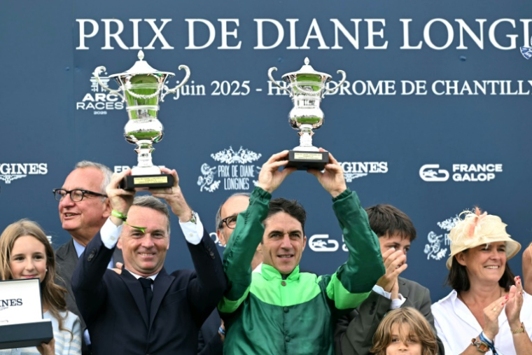 Le Belge Christophe Soumillon, qui montait Gezora (à droite) et l'entraîneur français Francis-Henri Graffard (à gauche) brandissent leurs trophées après avoir remporté le Prix de Diane Longines à l'hippodrome de Chantilly, le 15 juin 2025 ( AFP / Hugo MATHY )
