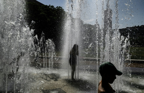 Des enfantts se rafraîchissent sous les jets d'eau d'une fontaine à Lyon, le 25 juin 2025  ( AFP / JEFF PACHOUD )