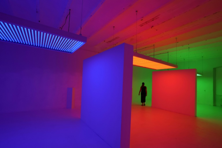 Une femme entre dans l'œuvre "Chromosaturation" de Carlos Cruz Diez, lors de l'exposition "Plein Soleil" organisée par De Renava à la caserne Montlaur de Bonifacio en partenariat avec le Centre Pompidou de Paris, le 2 juillet 2025 ( AFP / Pascal POCHARD-CASABIANCA )