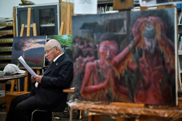 Masaki Hironaka, un survivant de la bombe atomique, assis parmi des peintures réalisées par des élèves pour préserver les témoignages des survivants, le 29 mai 2025 à Hiroshima ( AFP / Richard A. Brooks )