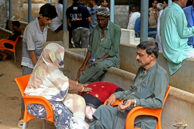 Des proches de victimes attendent des nouvelles après l'effondrement d'un immeuble d'habitation à Karachi, le 4 juillet 2025 ( AFP / Rizwan TABASSUM )