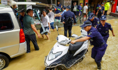 Une équipe aide à déplacer du matériel dans une rue inondée à Congjiang, dans la province de Guizhou, au sud-ouest de la Chine, le 24 juin 2025 ( AFP / STR )