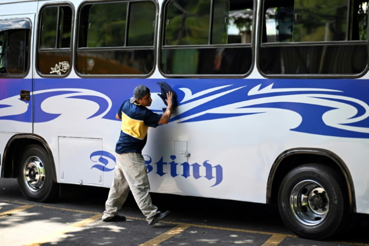 Carlos Sanchez nettoie un bus dans le quartier du 10 de Octubre à San Marcos, au Salvador, le 14 juin 2025 ( AFP / Marvin RECINOS )
