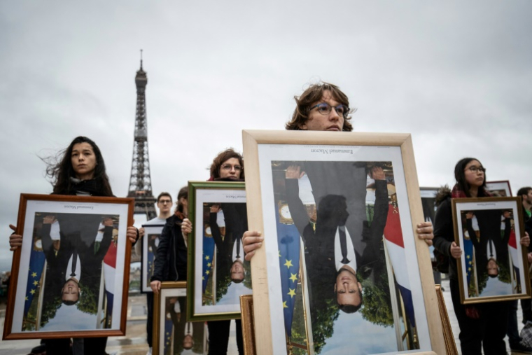 Des militants de l'association Action non violente - Cop21 (ANV-Cop21) tiennent des portraits à l'envers du président Emmanuel Macron décrochés dans différentes mairies, le 8 décembre 2019 sur l'esplanade du Trocadéro, à Paris ( AFP / Thomas SAMSON )
