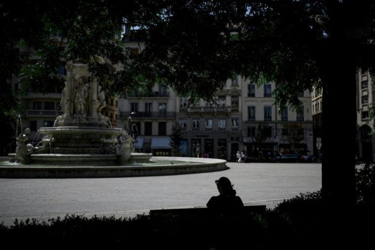 Une personne est assise à l'ombre sur la place des Jacobins, le 25 juin 2025 à Lyon ( AFP / JEFF PACHOUD )