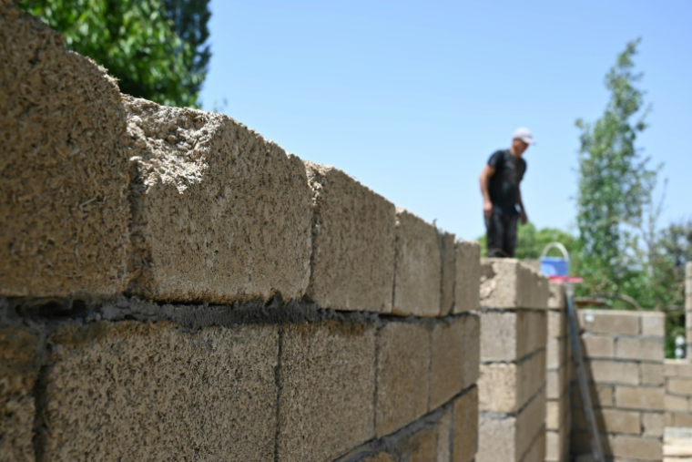 Des ouvriers construisent une maison avec des parpaings en riz, dans le village de Kyzyl-Kiya, dans le sud du Kirghizistan, le 22 mai 2025 ( AFP / Guliza Urustambek kyzy )