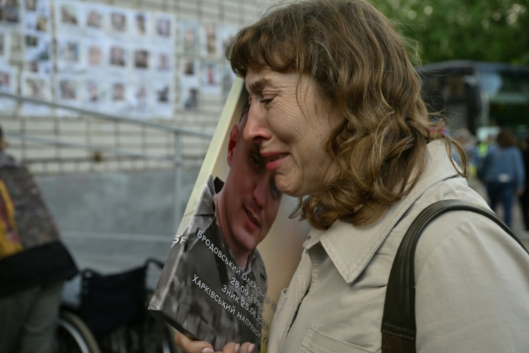 Lioubov Brodovska pleure en tenant un portrait de son fils disparu, Olexandre, en attendant l'arrivée de prisonniers de guerre ukrainiens libérés par la Russie, le 26 juin 2025 dans la région de Tcherniguiv (Ukraine) ( AFP / Genya SAVILOV )