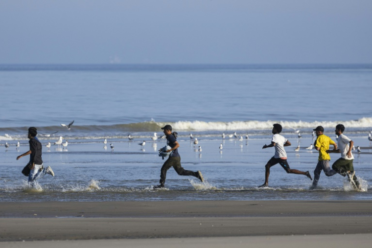 Des migrants courent sur la plage d'Equihen (Pas-de-Calais), le 30 juin 2025, pour tenter d'embarquer à destination de l'Angleterre ( AFP / Sameer Al-DOUMY )