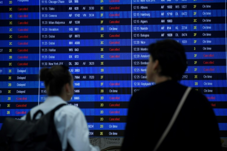 Des voyageurs regardent le panneau des départs du terminal 2 de l'aéroport Roissy-Charles de Gaulle, dans la banlieue nord-est de Paris, le 16 septembre 2022 ( AFP / JULIEN DE ROSA )