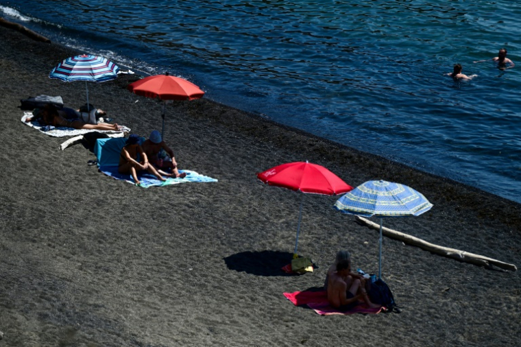 Des estivants à l'ombre de leurs parasols sur la plage de Cap d'Agde dans le sud de la France le 1er juillet 2025 ( AFP / GABRIEL BOUYS )