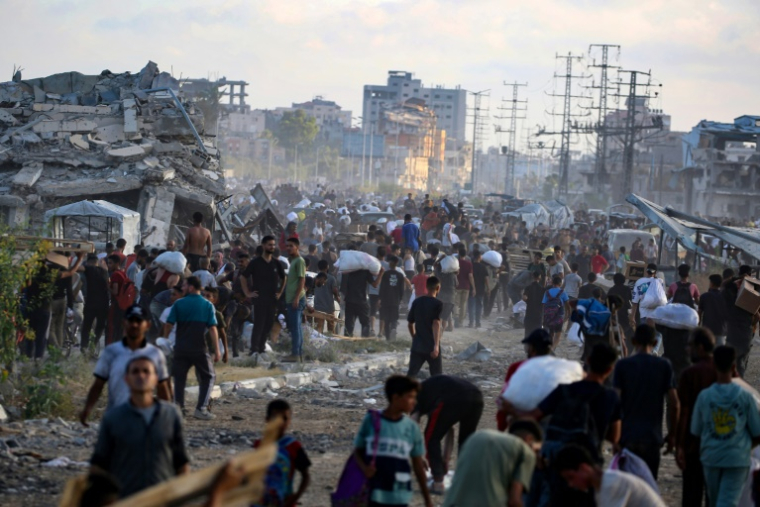 Des Palestiniens marchent le long d'une route de retour d'un point de distribution d'aide de la Fondation humanitaire de Gaza (GHF,) près du camp de réfugiés de Nousseirat, dans le centre de la bande de Gaza, le 25 juin 2025 ( AFP / Eyad BABA )