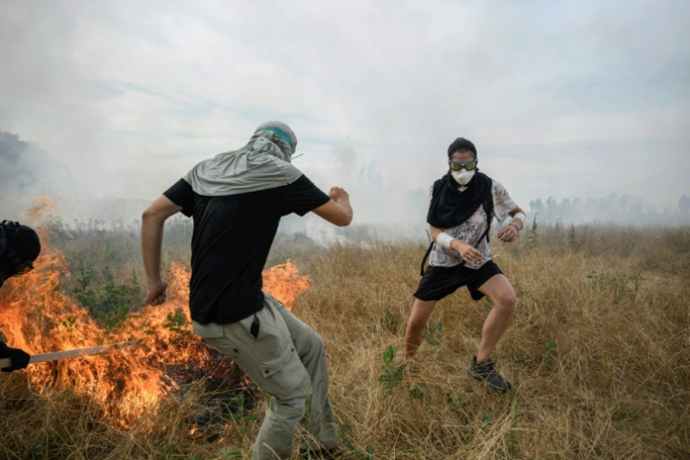 Des manifestants éteignent un feu déclenché par une grenade lacrymogène tirée par la police lors d'un rassemblement contre le projet d'autoroute A69, à Morens-Scopont, dans le sud de la France, le 5 juillet 2025 ( AFP / Ed JONES )