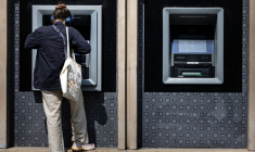 Une femme retire de l'argent à un distributeur automatique bancaire, le 3 juin 2025 à Paris ( AFP / JOEL SAGET )