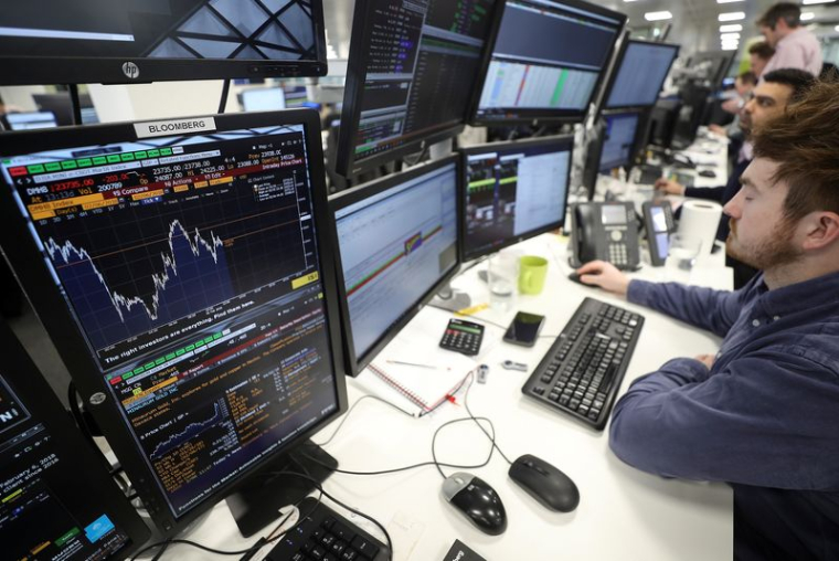 Des traders examinent des informations financières sur des écrans d'ordinateur sur le parquet de négociation d'IG Index à Londres