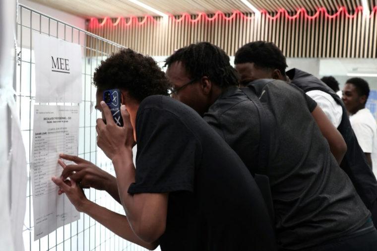 Des lycéens regardent fébrilement les résultats du baccalauréat affichés dans leur établissement de Saint-Ouen (Seine-Saint-Denis) le 4 juillet 2025 ( AFP / Thibaud MORITZ )