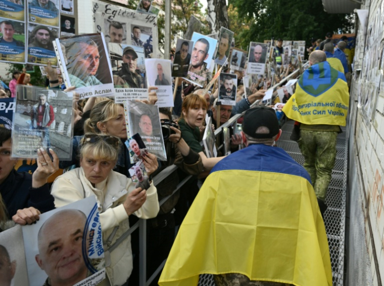 Des prisonniers de guerre ukrainiens libérés passent devant une foule brandissant des portraits de proches disparus ou prisonneirs, à leur arrivée après un échange de prisonniers dans la région de Tcherniguiv (Ukraine), le 26 juin 2025 ( AFP / Genya SAVILOV )