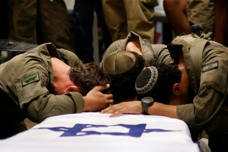 Des soldats israéliens se recueillent sur la dépouille du capitaine Reei Biran, tué dans la bande de Gaza, lors de ses funérailles dans la communauté de Nahalal, dans le nord d'Israël, le 11 juillet 2025 ( AFP / Jalaa MAREY )