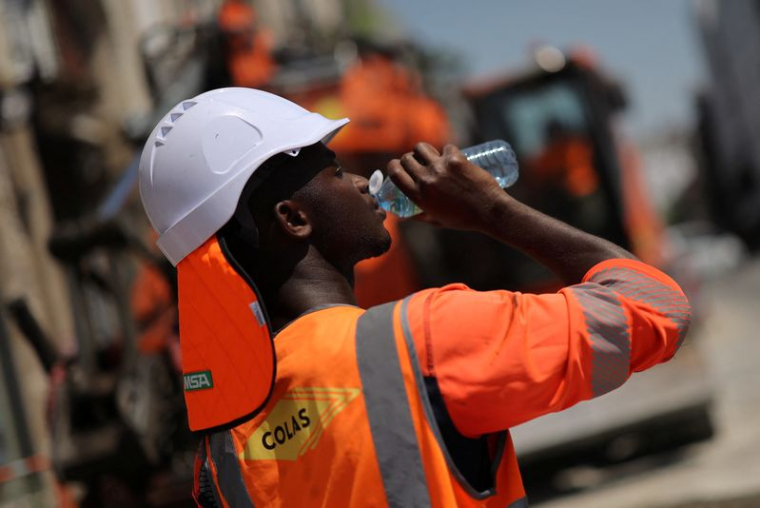 Un travailleur boit de l'eau sur un chantier de construction, lors d'une journée chaude et ensoleillée à Nantes