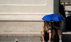 Des personnes utilisent un parapluie pour s'abriter du soleil près de la Pyramide du Louvre lors d'une vague de chaleur, à Paris, le 26 juin 2019 ( AFP / Kenzo TRIBOUILLARD )