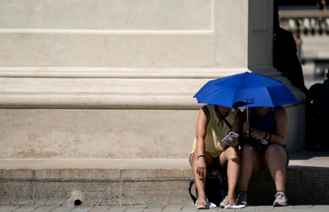 Des personnes utilisent un parapluie pour s'abriter du soleil près de la Pyramide du Louvre lors d'une vague de chaleur, à Paris, le 26 juin 2019 ( AFP / Kenzo TRIBOUILLARD )
