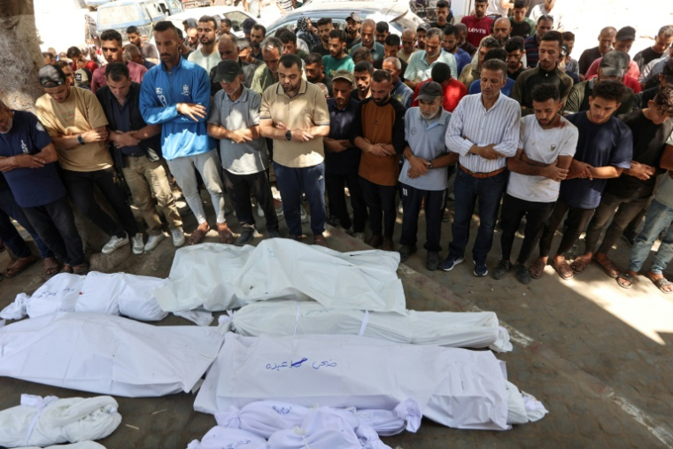 Des Palestiniens se recueillent devant des corps enveloppés dans des draps blancs, le 3 juillet 2025 dans la ville de Gaza ( AFP / Omar AL-QATTAA )
