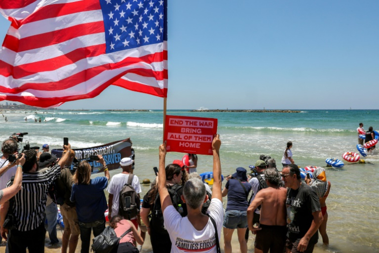 Des manifestants se rassemblent, à l'appel des familles des otages israéliens retenus à Gaza, sur une plage de Tel-Aviv, pour appeler les Etats-Unis à intervenir pour la libération des otages et pour un cessez-le-feu, le 4 juillet 2025 ( AFP / Jack GUEZ )