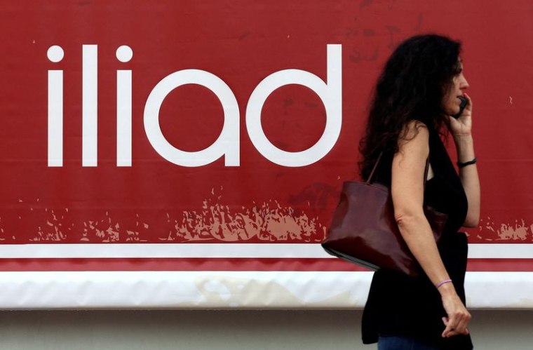 Une personne au téléphone devant le Logo d'Iliad