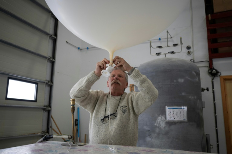 Le météorologue norvégien Trond Robertsen prépare un ballon de données météorologiques pour l'envoyer le plus haut possible à la station météorologique de la côte nord du territoire norvégien isolé de l'île aux Ours (Bjornoya), le 5 avril 2025 ( AFP / Olivier MORIN )