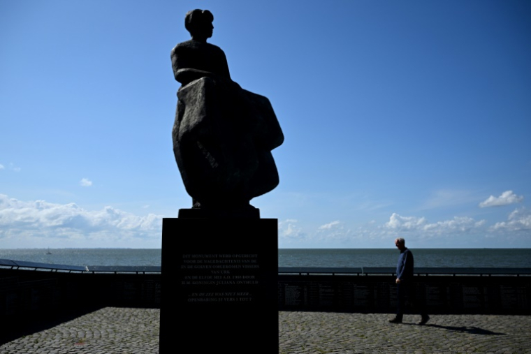 Un homme passe à côté du d'une statue de femme, dos à la mer, représentant les mères et épouses de pêcheurs disparus en mer à Urk, le 3 juillet 2025 aux Pays-Bas ( AFP / Nicolas TUCAT )