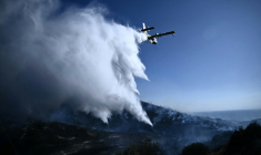 Un avion Canadair de lutte contre les incendies largue de l'eau sur un feu de forêt, près de Thymari, au sud-est d'Athènes, le 26 juin 2025 en Grèce ( AFP / Aris MESSINIS )