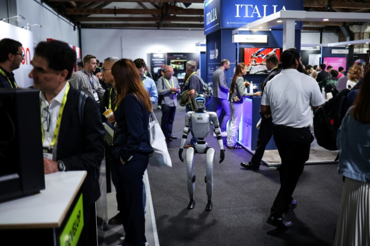 Un robot parmi des visiteurs au salon de l'IA à Londres, le 11 juin 2025 ( AFP / HENRY NICHOLLS )