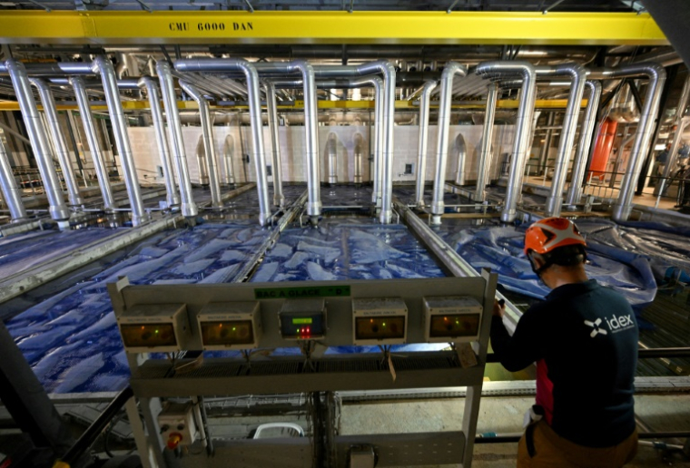 Un technicien effectue des vérifications sur le réseau de climatisation et de chauffage géré par Idex, dans le quartier d'affaires parisien de La Défense, le 16 juin 2022 ( AFP / EMMANUEL DUNAND )
