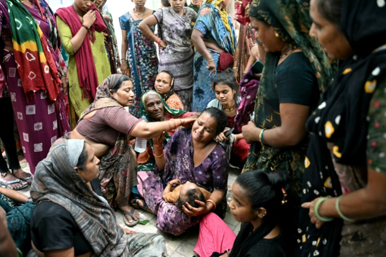 Des femmes assises devant la morgue de l'hôpital d'Ahmedabad pleurent leurs proches, tués la veille après le crash du vol 171 d'Air India dans un quartier résidentiel, le 13 juin 2025 en Inde ( AFP / Punit PARANJPE )