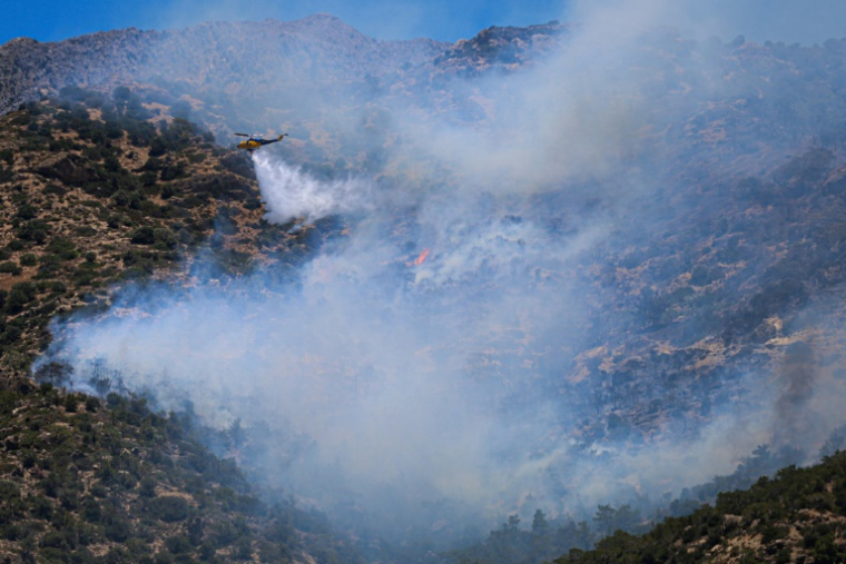 Un hélicoptère largue de l’eau sur un incendie de forêt qui s’est déclaré à Ierapetra, sur l’île grecque de Crète, le 3 juillet 2025 ( AFP / Costas METAXAKIS )