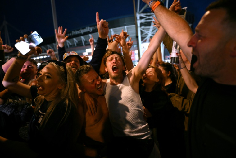 Les fans du groupe de rock britannique Oasis se réjouissent à l'extérieur du Principality Stadium à Cardiff le 4 juillet 2025 ( AFP / Oli SCARFF )