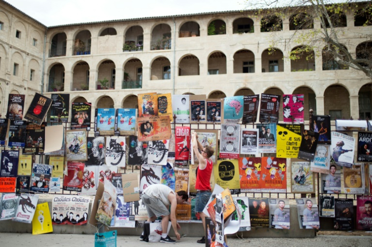 Les artistes du Festival Off d'Avignon accrochent des affiches pour promouvoir leurs pièces, à Avignon, le 5 juillet 2016 ( AFP / BERTRAND LANGLOIS )