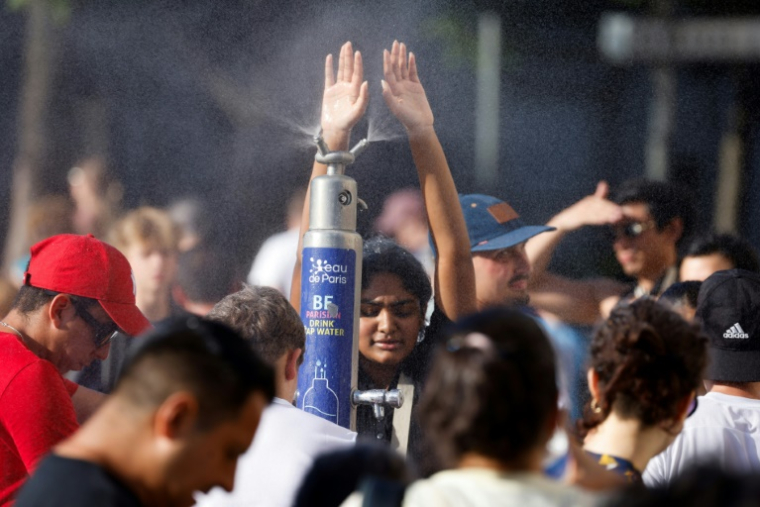 Des personnes se rafraîchissent à une fontaine à Paris, le 30 juin 2025 ( AFP / Ludovic MARIN )