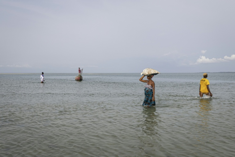 Une habitante porte des denrées après les avoir déchargées d'une pirogue sur l'île de Nyangai, au large de la Sierra Leone, le 29 avril 2025 ( AFP / PATRICK MEINHARDT )