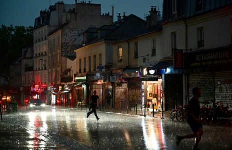 Des personnes courent se mettre à l'abri lors d'un violent orage dans le 20e arrondissement à Paris, le 25 juin 2025 ( AFP / Christophe DELATTRE )